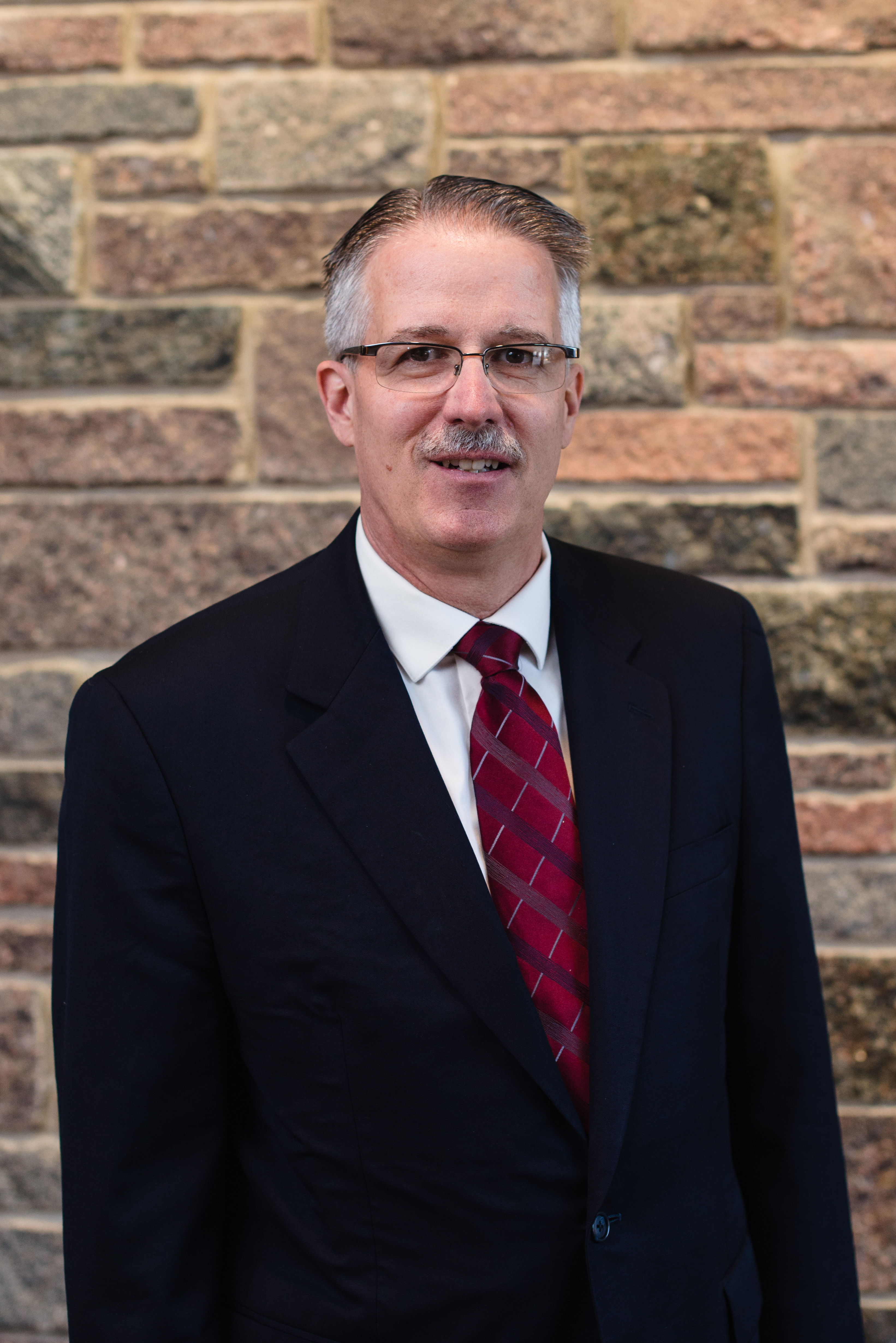 MCC CEO Rev. Dr. Curtiss Paul DeYoung stands in front of a stone wall