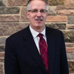 MCC CEO Rev. Dr. Curtiss Paul DeYoung stands in front of a stone wall